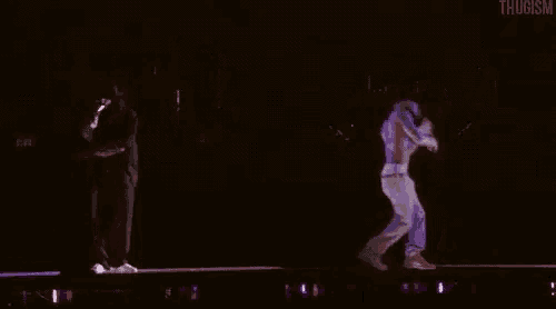 two men are standing on a stage in the dark .