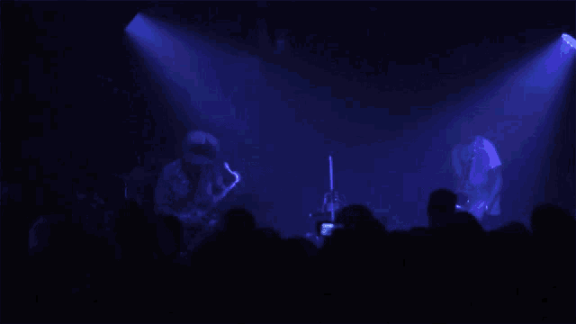 a group of people watching a concert with purple lights