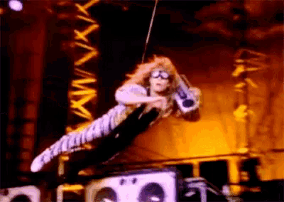 a man is flying through the air on a stage holding a microphone .
