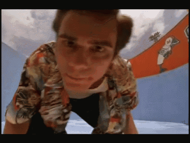 a man in a hawaiian shirt is looking down at something