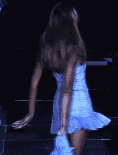 a woman in a blue dress is walking down a dark street