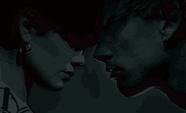 a man and a woman are looking at each other in the dark