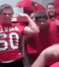 a man in a red jersey with the number 50 on it is flexing his muscles in a crowd of people .