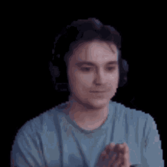 a man wearing headphones and a blue shirt is smiling and making a funny face .
