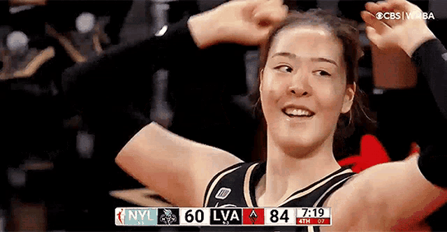 a female basketball player celebrates with her hands in the air during a game