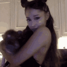 ariana grande is wearing a cat costume and holding a stuffed animal .