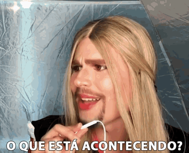 a man with long blonde hair and a beard says " o que esta acontecendo ? "