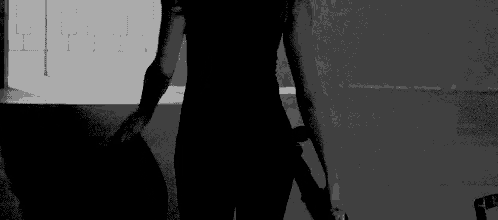 a black and white photo of a woman holding a sword in a dark room .
