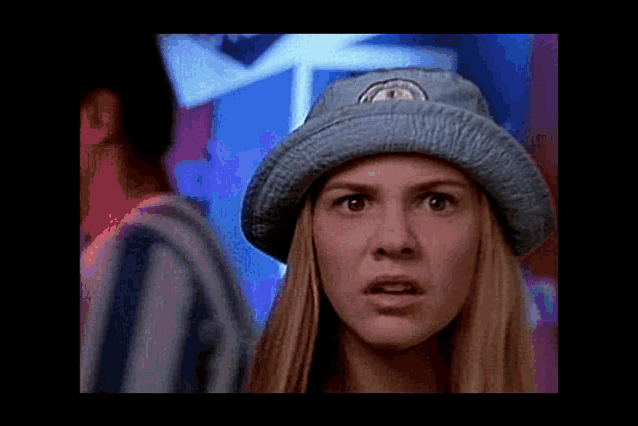 a woman wearing a blue hat with a logo on it looks surprised and shocked