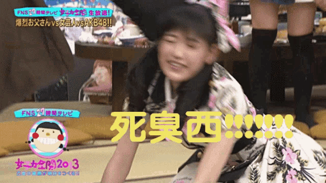 a girl in a floral dress is laying on the floor in front of a sign that says fns 20 3