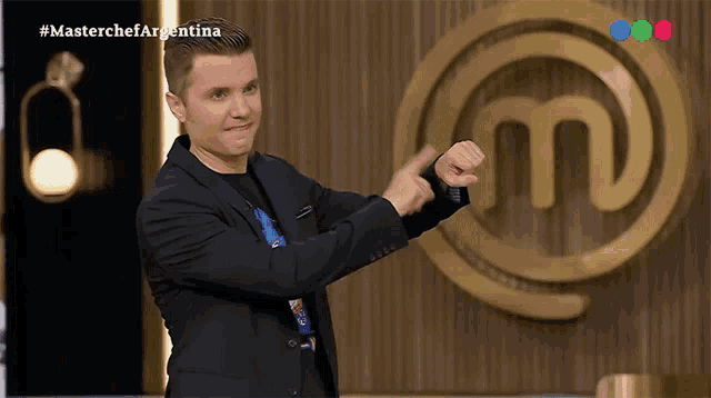 a man in a suit stands in front of a master chef argentina logo