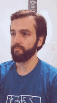 a man with a beard is wearing a blue shirt that says t.h.a.y.