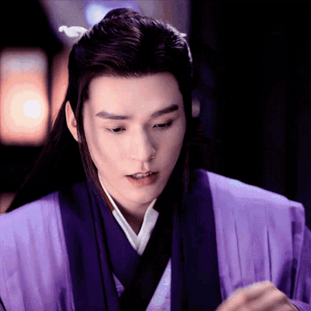 a man with long hair is wearing a purple kimono