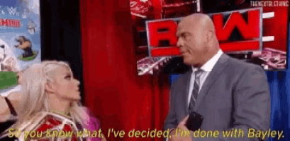 a man in a suit and tie is talking to a woman in front of a wwe sign .