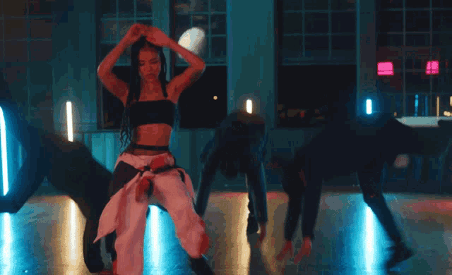 a woman in a black top and white pants is dancing in front of blue lights