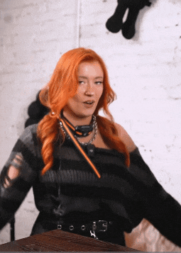 a woman with red hair is wearing a black striped top