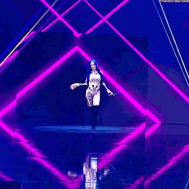 a woman with long blue hair is dancing on a stage