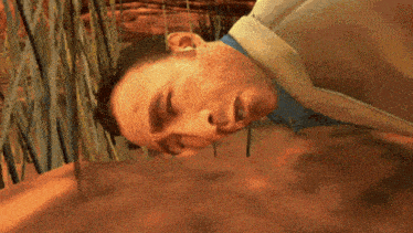 a man in a blue shirt is laying on the ground with his eyes closed