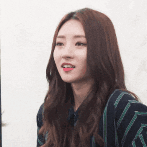 a woman with long hair is wearing a striped shirt and making a funny face