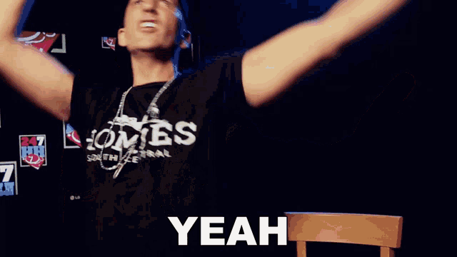a man wearing a shirt that says yeah is making a hand gesture