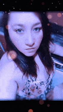 a woman in a floral top is taking a selfie in front of a washing machine