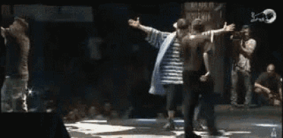 a group of people are dancing on a stage in front of a crowd of people .