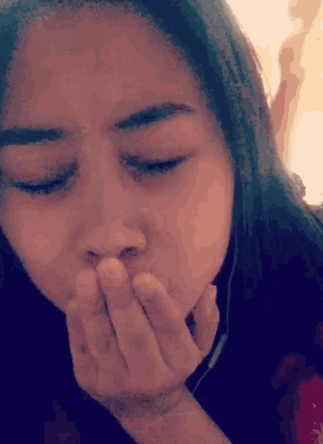 a close up of a woman covering her mouth with her hands