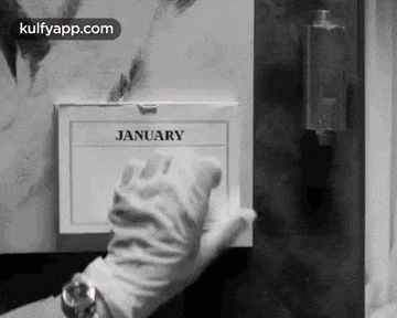 a person wearing white gloves is holding a calendar that says january on it .