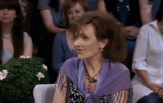 a woman wearing a purple scarf is sitting in a crowd