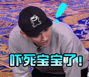 a man wearing a black hat with a teddy bear on it is kneeling down with chinese writing above him