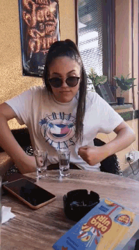 a woman wearing sunglasses sits at a table with a box of big win chips on it