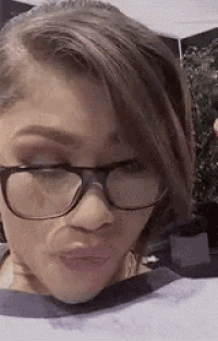 a woman wearing glasses and a striped shirt is making a funny face .