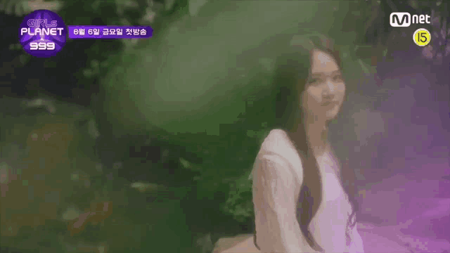 a woman with long hair is sitting in a purple foggy forest .