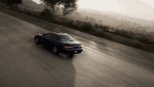 a black car is driving down a road with a license plate that says rb