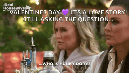 two women are sitting at a table with bottles of alcohol and one of them is asking the question who is hunky dory ?