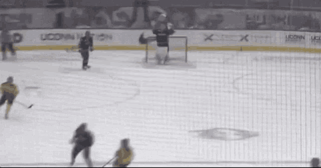 a hockey game is being played in front of a banner that says uconn university
