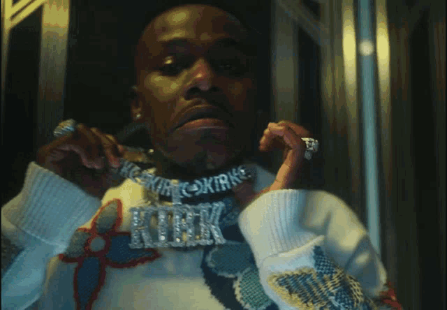 a man wearing a sweater and a necklace with kirk on it
