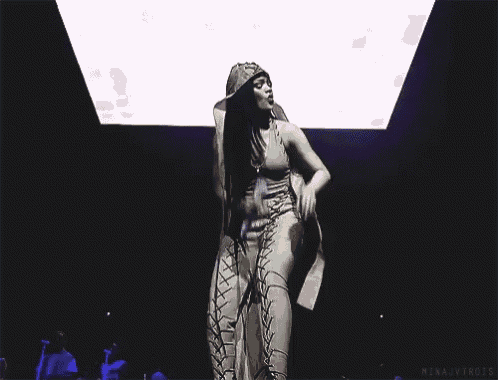 a woman is dancing on a stage in front of a screen that says ' mina jvtrots ' on it