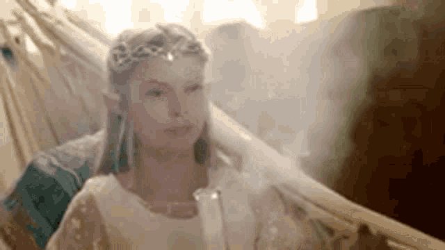 a woman is sitting in a hammock wearing a crown and a white dress .