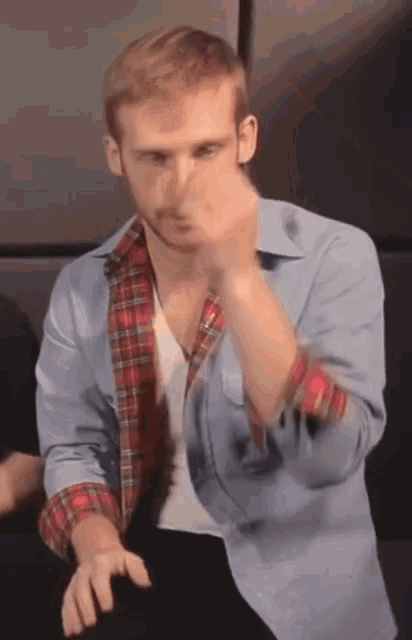 a man in a plaid shirt is making a gesture
