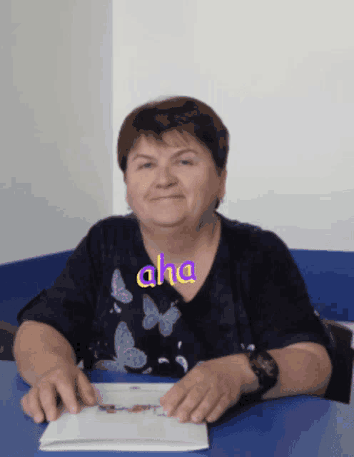 a woman wearing a blue shirt with butterflies and the word aha written on it