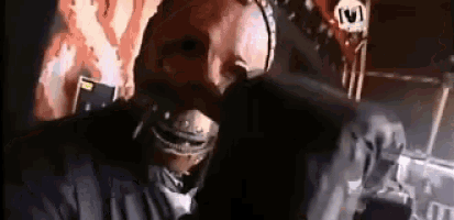 a man wearing a mask is sitting in front of a microphone .