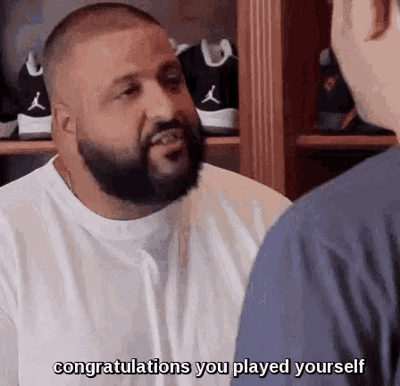 a man with a beard is talking to another man in front of a shelf of shoes .