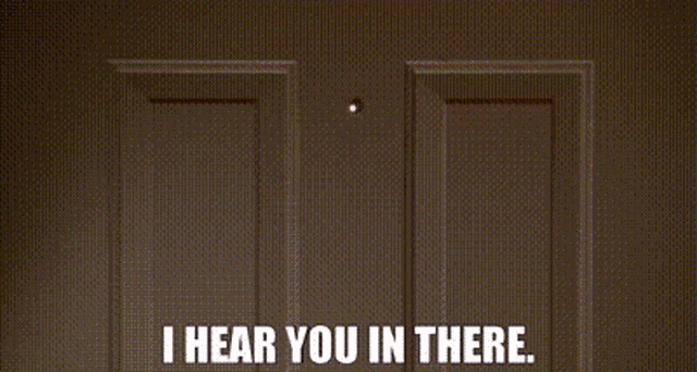 a man is covering his mouth with his hand while another man says `` i hear you in there . ''