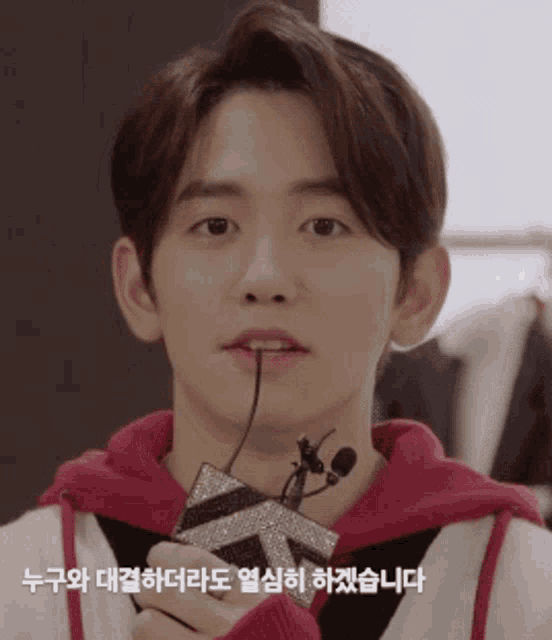 a young man in a red hoodie holds a microphone in his hand