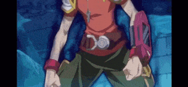 a man in a red shirt and green pants is standing in front of a blue wall with his fist in the air .