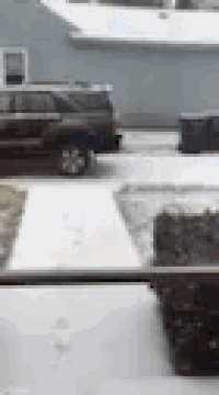a black suv is parked in the snow in front of a house