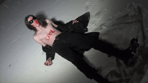 a shirtless man laying in the snow with sexy written on his chest