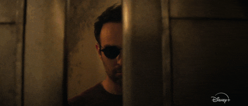 a man wearing sunglasses is behind a door that says disney on it