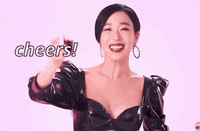 a woman in a black dress is holding a glass of wine in her hand and says cheers .